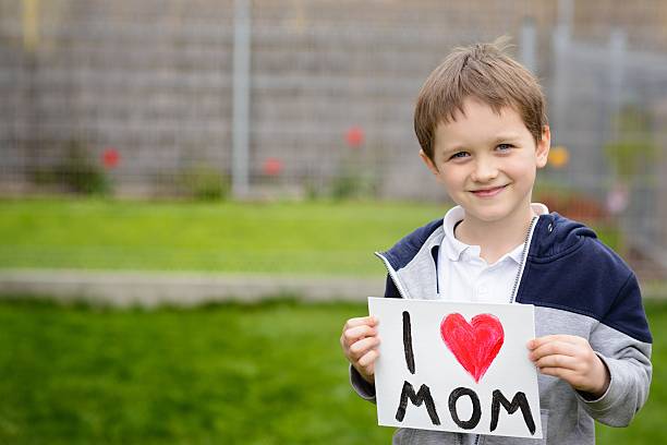 istock 7 years boy holding a greeting card for his mother 528441482