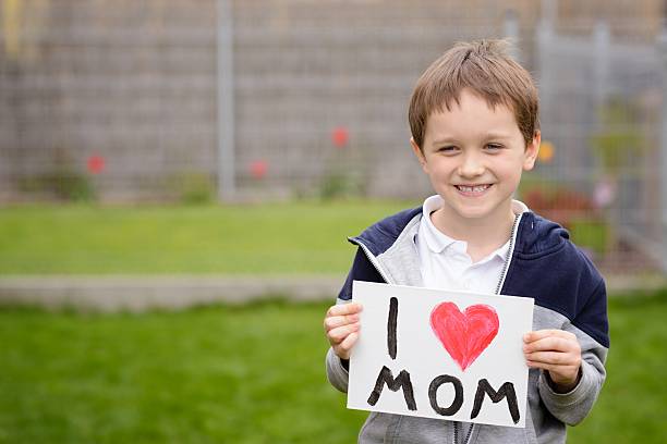 istock 7 years boy holding a greeting card for his mother 528441552