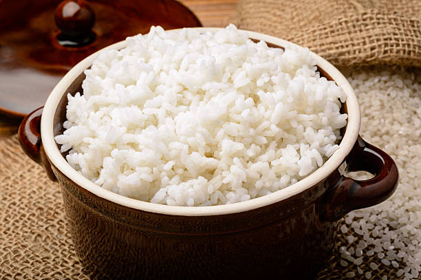 Boiled white rice in ceramic pot on wooden background. stock photo