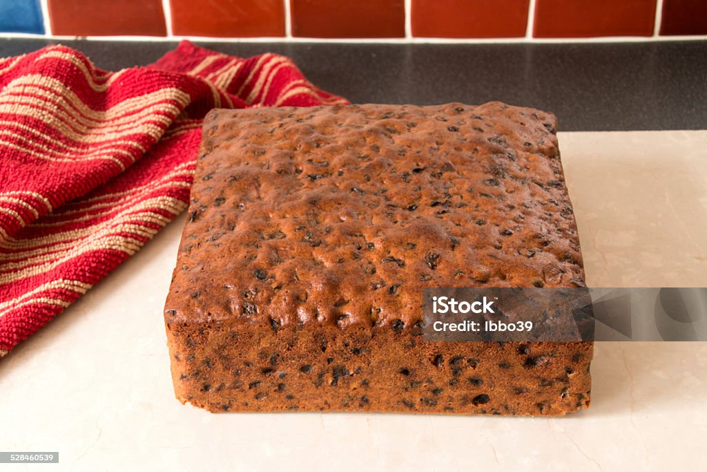 Rich fruit cake, square cake cooked ready to ice Rich fruit cake removed from baking tin placed on cream marble worktop Baked Stock Photo