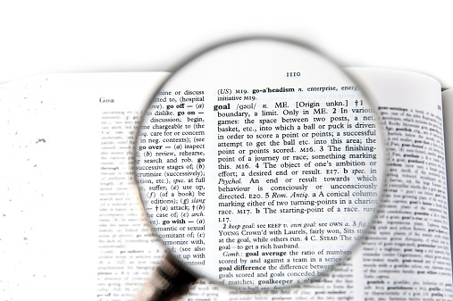 A magnifying glass on the word goal on a dictionary