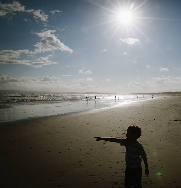 A portrait of a little boy poiting at the sea.