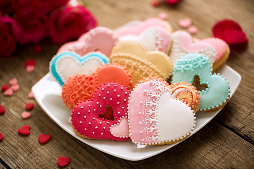 Different colored festive cookies hearts on wooden desk