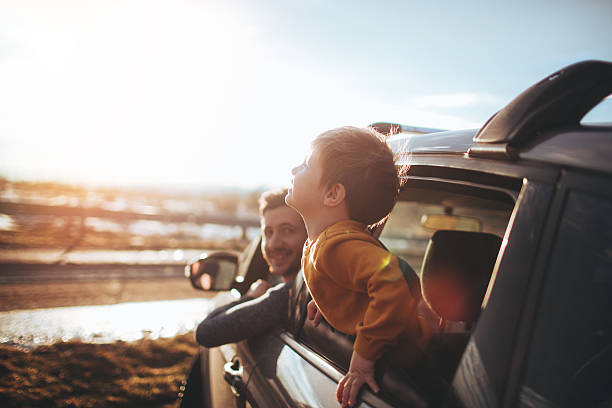 Little boy and his father looking trough the window of a car during the road trip