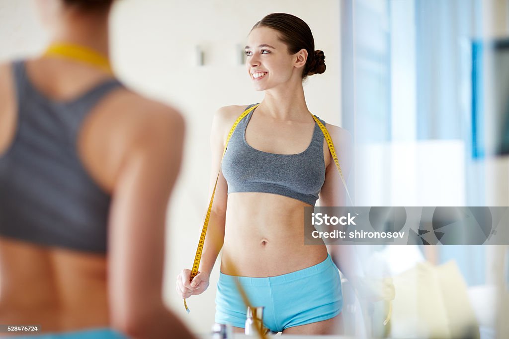 Perfect results of fitness Young woman standing with tape measure in front of mirror Women Stock Photo