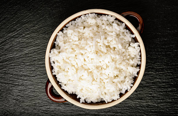 istock Boiled white rice in ceramic pot on black background. 528477850