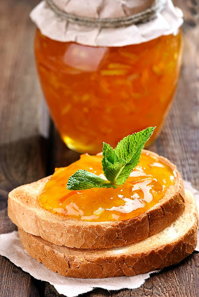 Orange jam on bread Orange jam on bread on wooden table marmalade stock pictures, royalty-free photos & images