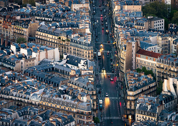 Night traffic on a road in Montparnasse, Paris, passing traditional Parisien residential apartment blocks, shops and restaurants.