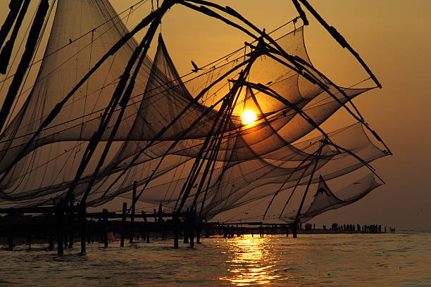 Chinese fishing net, Kochi, Kerala- India. Chinese fishing nets are fishing nets that are fixed land installations for fishing, which are used for a very unique and unusual method of fishing. Operated from the shore, these nets are set up on bamboo and teak poles and held horizontally by huge mechanisms, which lower them into the sea. cochin kerala india chinese fishing net stock pictures, royalty-free photos & images