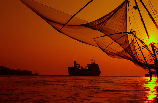 Chinese fishing net, Kochi, Kerala- India. Chinese fishing nets are fishing nets that are fixed land installations for fishing, which are used for a very unique and unusual method of fishing. Operated from the shore, these nets are set up on bamboo and teak poles and held horizontally by huge mechanisms, which lower them into the sea. cochin kerala india chinese fishing net stock pictures, royalty-free photos & images