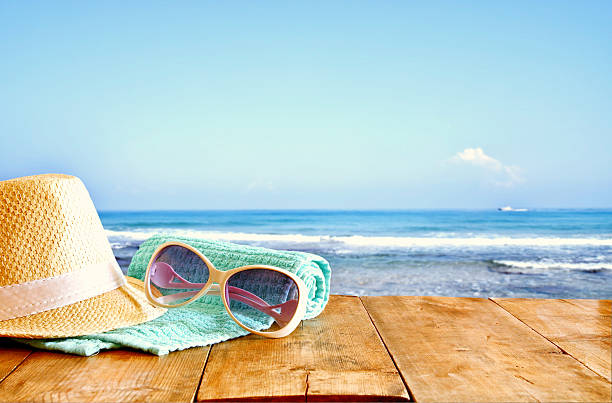 istock hat and sunglasses over wooden table and sea background 528484172