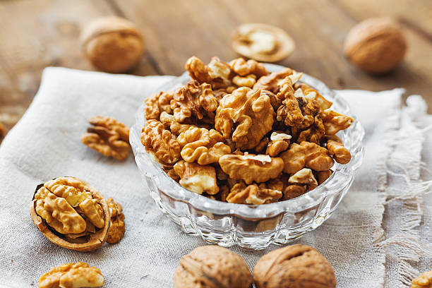 Glass bowl with walnuts on rustic homespun napkin. Healthy snack.