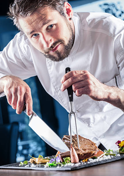 istock Professional chef in a restaurant prepares or cut up t-bone 528491034