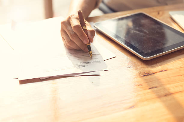 istock man's hand signing application form with tablet on wooden table 528491264