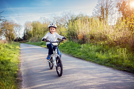 Boy learning to ride his bike on a country track road concept for safety and child development
