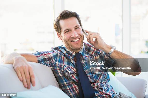 Cheerful Man Sitting On The Couch Making A Phone Call Stock Photo - Download Image Now