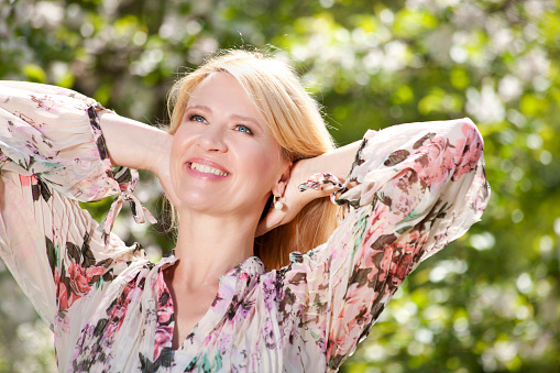 Happy middle age woman in front of flowering tree in spring