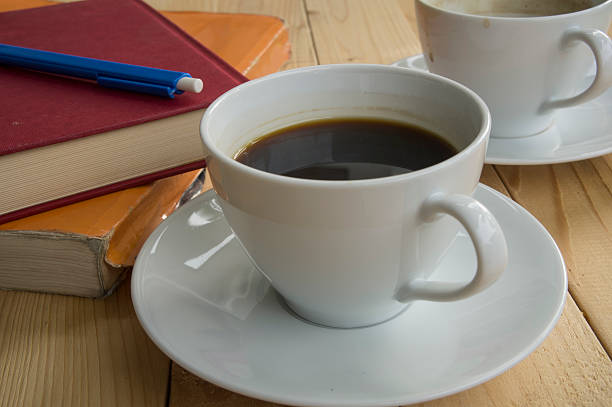 tazza di caffè buongiorno con penna rossa libro blu - brown candid caffein drink foto e immagini stock