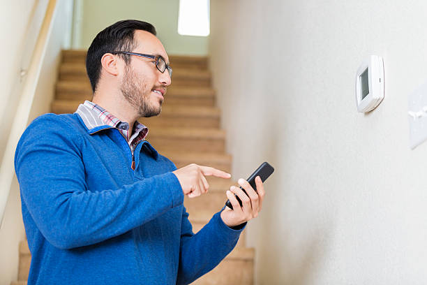 istock Man uses smart phone to control thermostat 528497016