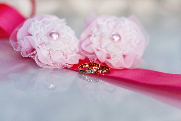 istock Wedding rings lying on pink tape at table with reflection 528497022