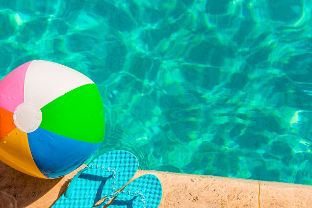 istock turquoise flip flops and ball on the edge of pool 528498787