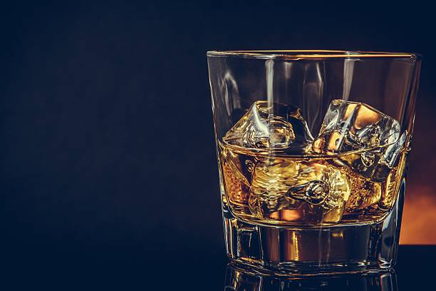 istock glass of whiskey on black background with reflection, warm atmosphere 528499390