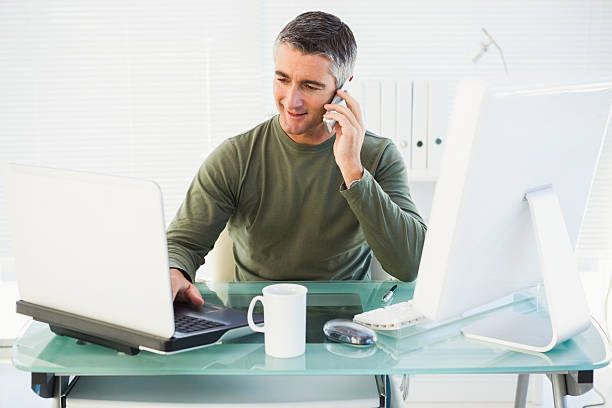 Happy man phoning and using laptop Happy man phoning and using laptop in his office animal call stock pictures, royalty-free photos & images