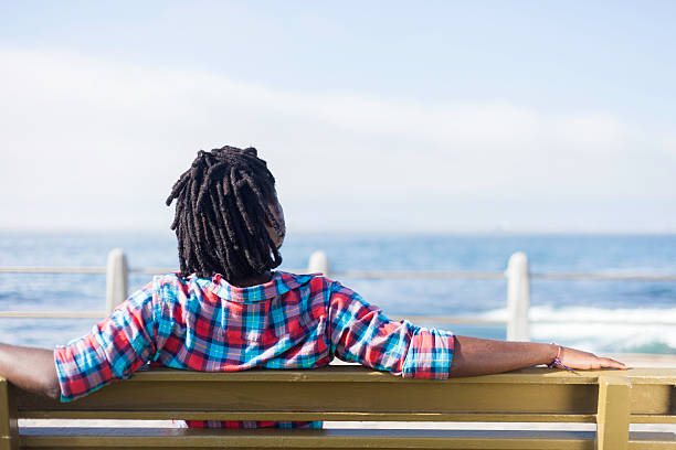 istock African man sitting on a bench by the the ocean 528499853