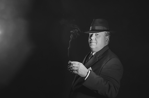 Vintage 1930s gangster holding cigar. Classic black and white portrait.
