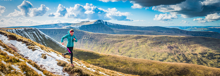 Active teenager trail running along rocky path high in the picturesque mountain wilderness of the Brecon Beacons National Park, Wales. ProPhoto RGB profile for maximum color fidelity and gamut.