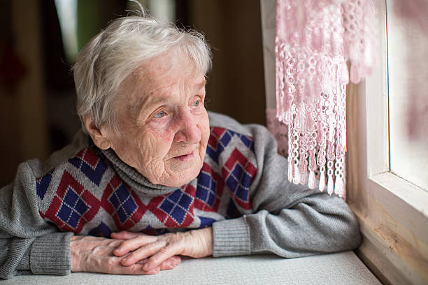 istock An elderly woman sits and looking out the window. 528503500