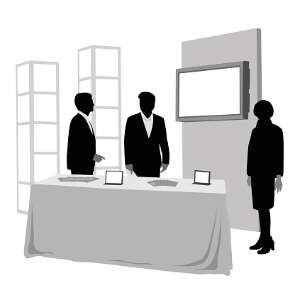 Business men and a business woman are attending a booth at a convention.  They have a table and a large display screen behing them.  This vector illustration is a silhouette them with greyscale details.