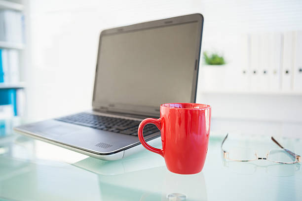 istock Laptop on desk with red mug and glasses 528530057