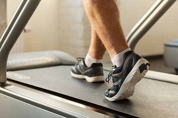 Exercising on treadmill. Close-up of man walking by treadmill in sports club treadmill stock pictures, royalty-free photos & images