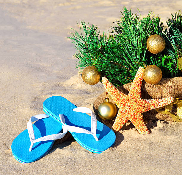 istock Christmas tree with christmas balls, slippers, starfish on beach 528535283