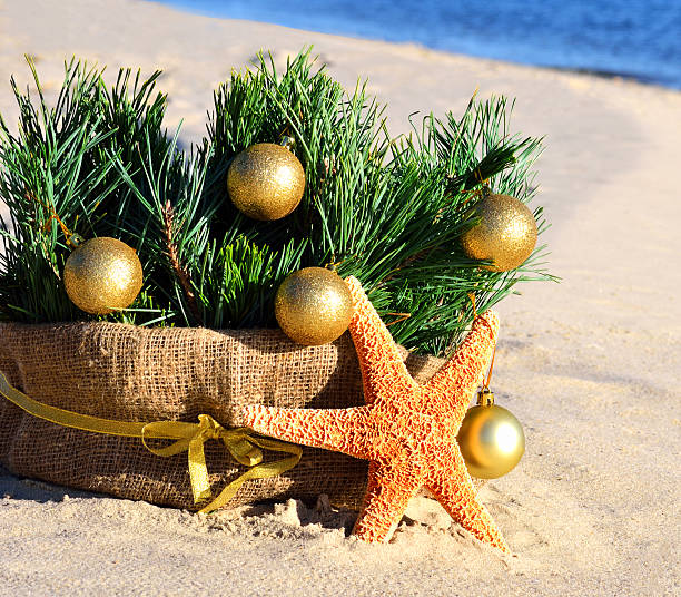 istock Christmas tree with golden christmas balls, starfish on beach 528535287