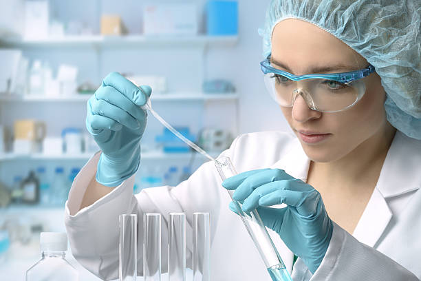 Young female tech or scientist performs protein assay Young female tech or scientist loads liquid sample into test tube with plastic pipette. Shallow DOF, focus on the hand with the tube. biologist stock pictures, royalty-free photos & images