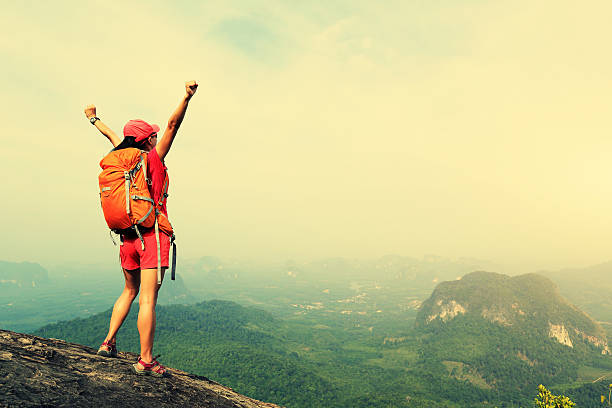 istock cheering successful woman hiker open arms at mountain peak 528557352