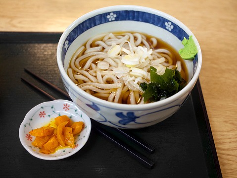 Udon served in bowl with takuan aside on serving tray