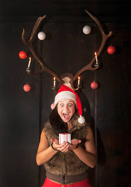 istock Mrs. Claus standing under decorated antlers, holding Christmas present 528560505