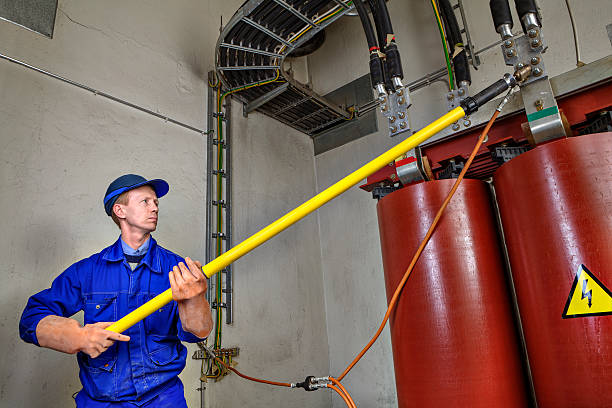 istock Worker uses insulating stick to earth grounding transformer. 528562524