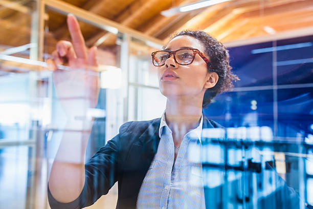 istock Young businesswoman with index finger on window panel 528562746