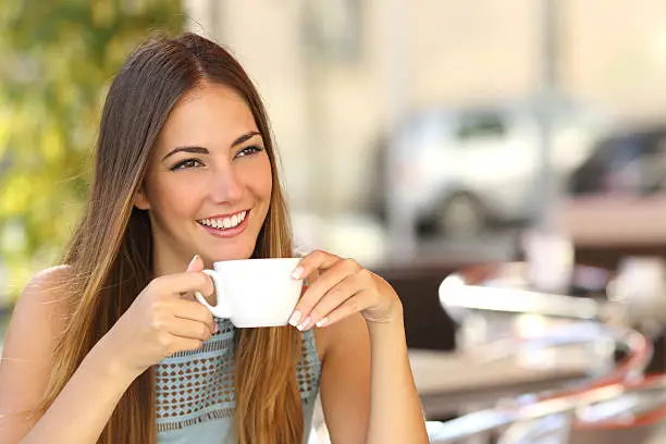 Photo of Pensive woman thinking in a coffee shop terrace