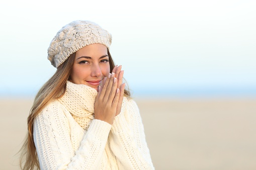 Woman warmly clothed in a cold winter on the beach with the sky in the background