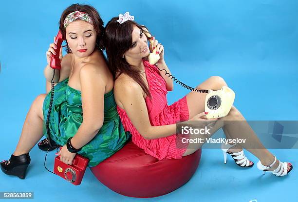 Two Young Women Calling On Phones On Blue Background Stock Photo - Download Image Now