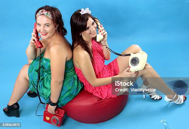 Two Young Women Calling On Phones On Blue Background Stock Photo - Download Image Now