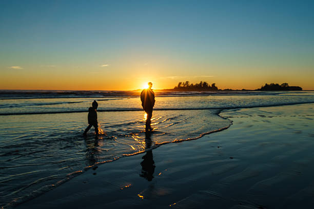 Father and son walking in the surf at Chesterman Beach in Tofino, British Columbia