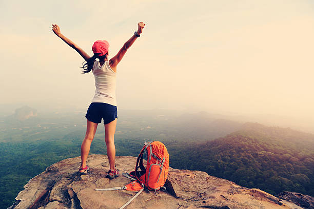 istock cheering successful woman hiker open arms at mountain peak 528564652