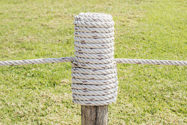 acercamiento de madera cuerda cansado en polos con hierba fondo. - wooden post wood grass string fotografías e imágenes de stock