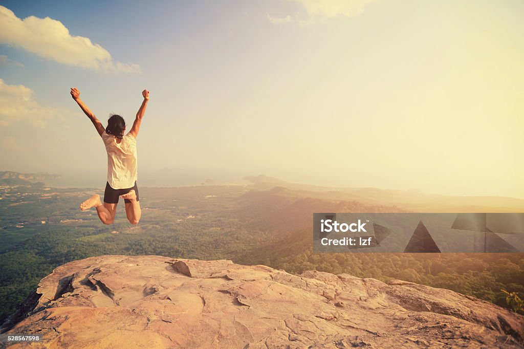 Jeune femme asiatique joyeuse saut au sommet de la montagne Rock - Photo de Falaise libre de droits